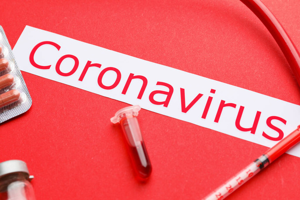 Test tube with blood sample and text Coronavirus on color background - Foto, immagini
