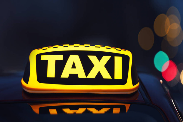 Taxi coche con letrero de techo amarillo en la calle de la ciudad por la noche, primer plano
 - Foto, imagen