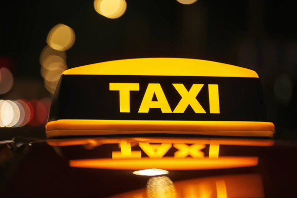 夜の街の通りに黄色の屋根の標識付きのタクシー車、クローズアップ - 写真・画像