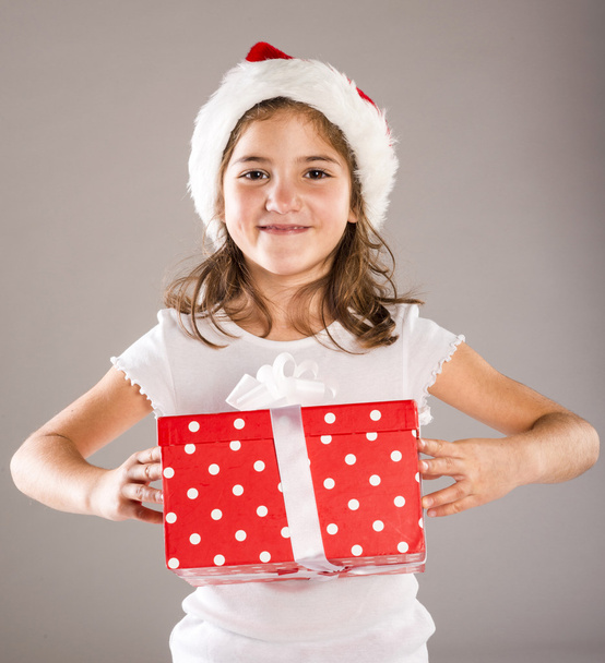 Small girl in santa hat with christmas gift - Fotó, kép