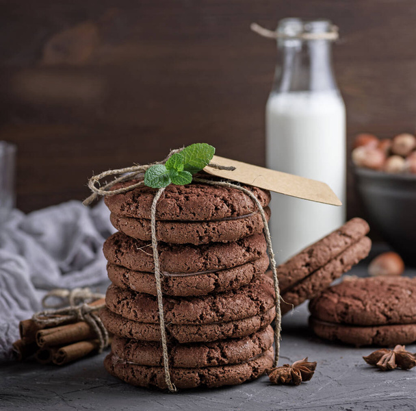 stack of chocolate chip cookies tied with a rope on a table and a bottle of milk behind - Foto, immagini