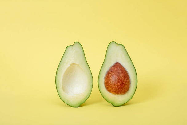 Two slices of avocado isolated on  yellow background with shadows . One slice with core. Design element for product label - Valokuva, kuva