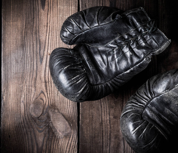 pair of old leather boxing gloves on a wooden background, vintage toning - Photo, Image