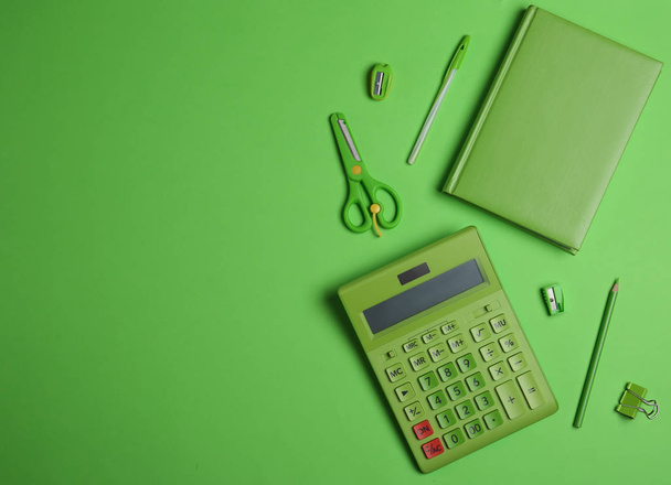 Flat lay composition with stationery and calculator on green background. Space for text - Φωτογραφία, εικόνα