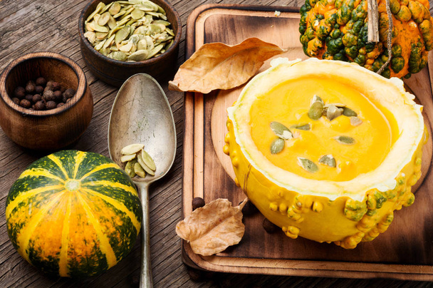Vegetarian pumpkin cream soup with seeds in pumpkin.Seasonal autumn food.Cream soup in pumpkin - 写真・画像