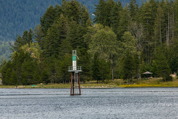 Pequeno farol perto da margem de um lago
 - Foto, Imagem