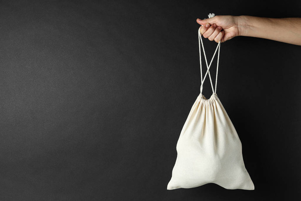 Woman holding full cotton eco bag on black background, closeup. Space for text - Fotoğraf, Görsel