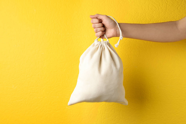Mujer que tiene una bolsa completa de algodón ecológico en el fondo amarillo, maquillaje - Foto, imagen