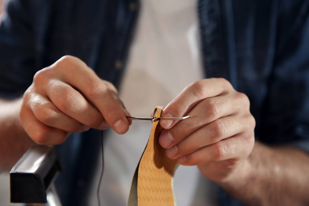 Man sewing piece of leather in workshop, closeup - Fotografie, Obrázek