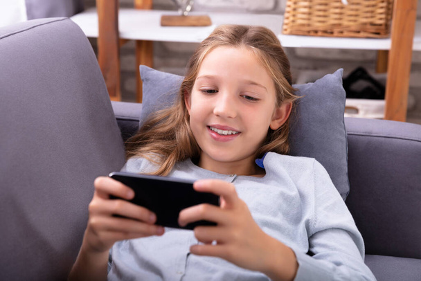 Portrait Of A Relaxed Girl On Sofa Using Mobile Phone - Foto, afbeelding
