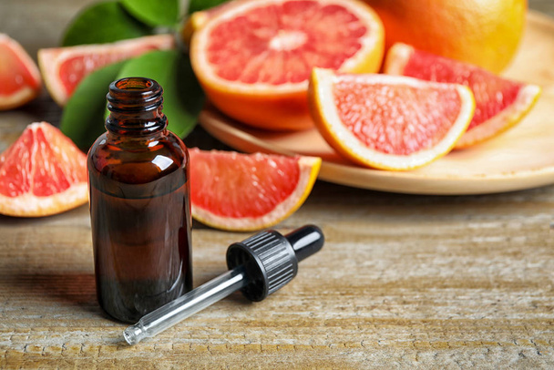 Citrus essential oil and grapefruits on wooden table. Space for text - Photo, image