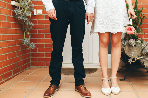 Damat ve gelinin ayakkabıları ve törenden sonra sımsıkı sarılmış küçük pembe gül buketi. Düğün konsepti. Düğün günü konsepti. - Fotoğraf, Görsel