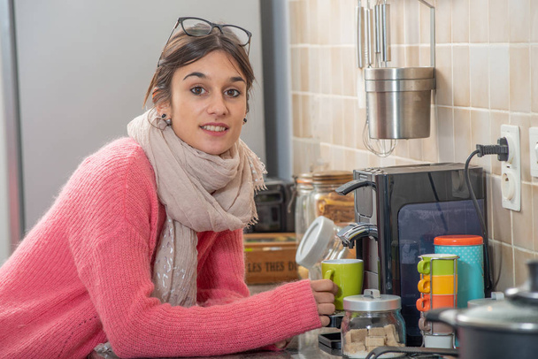 young brunette woman drinking a coffee in the kitchen - Fotó, kép
