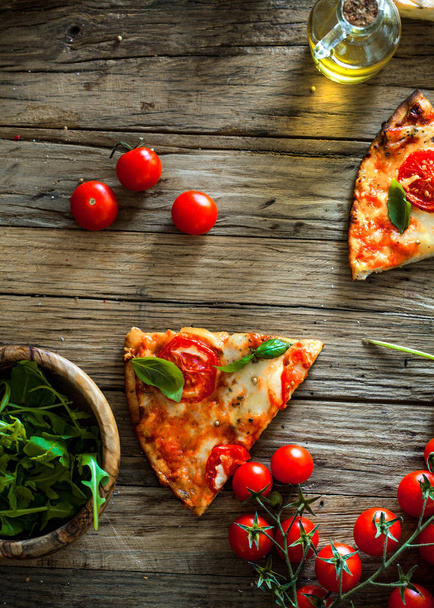 Pizza slice on wood with ingredients. Pizza with cheese, tomatoes and basil. Rustic italian pizza - Fotografie, Obrázek