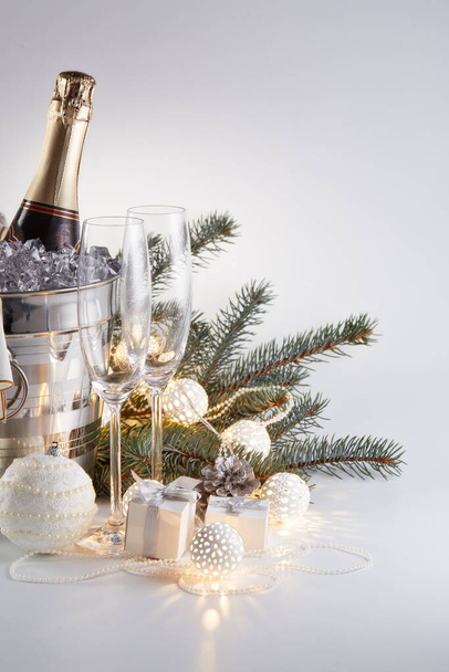 Still life with cooled champagne bottle  standing  in a bucket with ice, two champagne flutes and Christmas ornaments on a gray background, Christmas and New Year celebration - Φωτογραφία, εικόνα