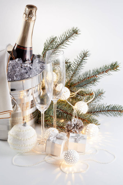 Still life with cooled champagne bottle  standing  in a bucket with ice, two champagne flutes and Christmas ornaments on a gray background, Christmas and New Year celebration - Foto, Bild