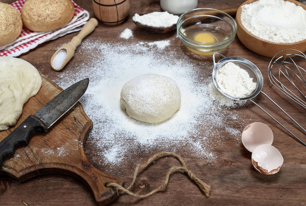 Mąka pszenna biała okrągłe ciasto, składniki na brązowy drewniany stół - Zdjęcie, obraz