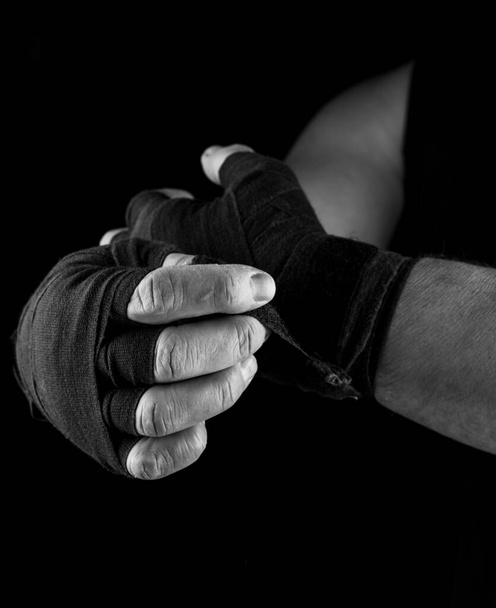 man wraps his hands in black textile bandage for sports, black and white photo - Fotografie, Obrázek