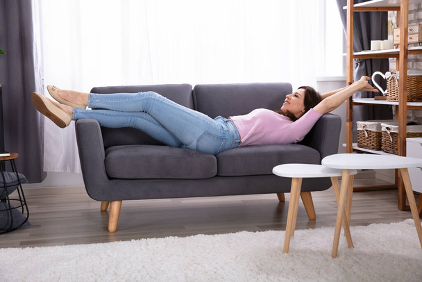 Smiling Young Woman Lying On Sofa At Home - Photo, Image