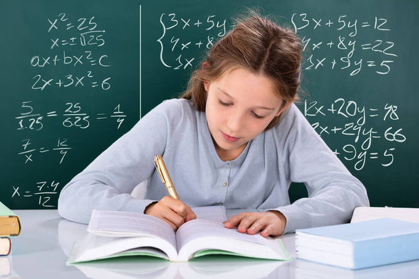 Portrait Of A Girl Doing Study In Front Of Green Chalkboard - Photo, Image