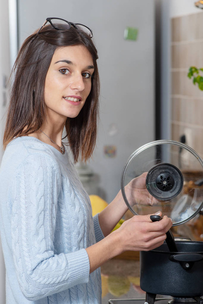 台所で料理をかなり若いブルネットの女性 - 写真・画像