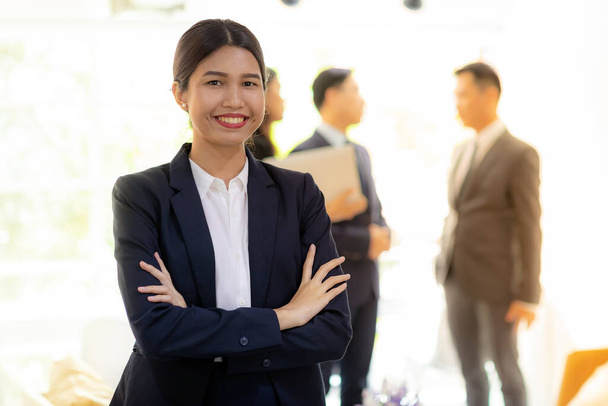 Portrait of asian businesswoman with business team in background at office window using for coporate working background - Foto, Bild