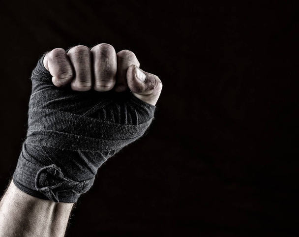 lifted up fist of athlete wrapped in black textile bandage, gesture of solidarity - Fotó, kép