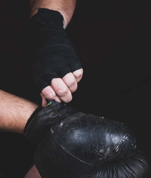 athlete puts on black leather boxing gloves before a fight, selective focus - Fotografie, Obrázek