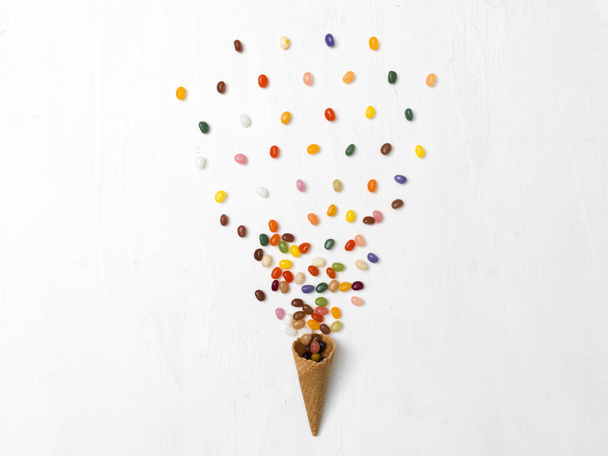 background with ice cream cone with many diferent colorful jelly beans on white background - Foto, imagen