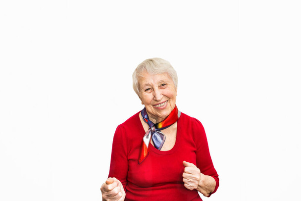 Old smiling woman with surprised expression on her face on red studio background. Human emotions concept. Positive emotional old lady standing indoor - Fotografie, Obrázek