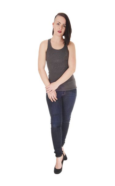 A beautiful young woman standing on white background in jeans and.a t-shirt with short black hair and her hands on her tight. - Foto, immagini