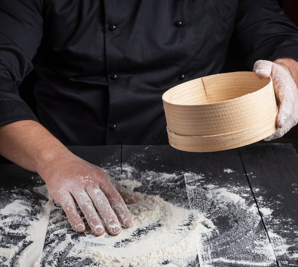 Chef prepares the dough of white flour, in your hand round wooden sieve - Zdjęcie, obraz