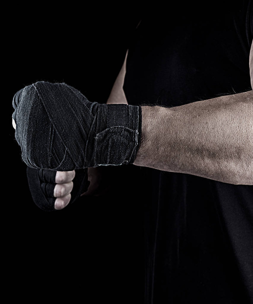 athlete is standing with a stretched arm bandaged, black background - Valokuva, kuva