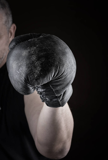 athlete is standing in a boxing rack, wearing black  leather gloves - Fotó, kép