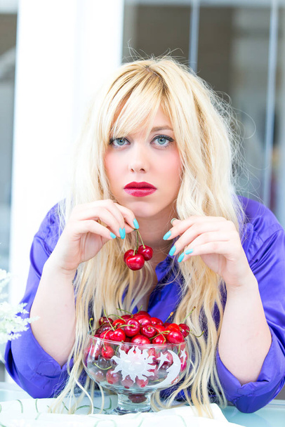 Blonde woman eating cherries - Фото, изображение