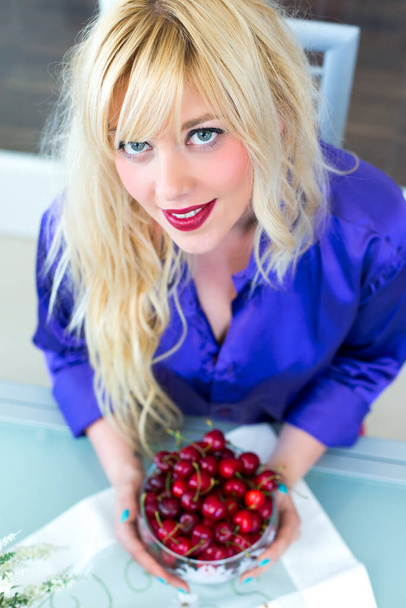 Blonde woman eating cherries - Foto, afbeelding
