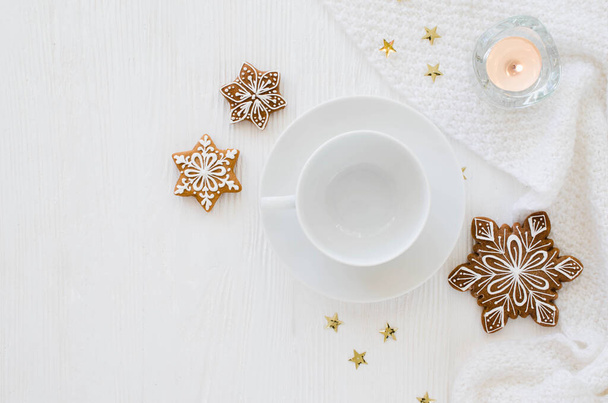 Christmas background. Empty white cup, gingerbread, candles and knitted scarf on a white wooden background. Light still life. Flat lay, top view, copy space - Photo, Image