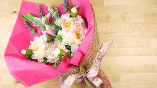 Λουλούδια τυλιγμένο σε ροζ ιστό και την εσσιανή σύγχρονη τάση περιτυλίγματος flatlay. - Φωτογραφία, εικόνα