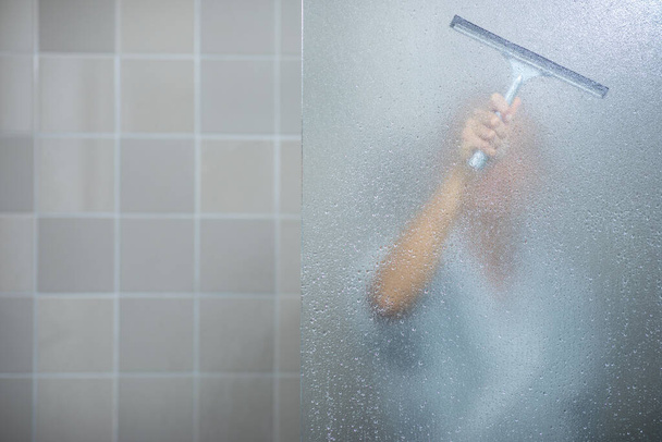 Woman taking a long hot shower washing her hair in a modern design bathroom - Фото, изображение