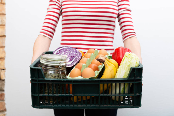 Woman holding box of grocery food and from store. Online grocery shopping service concept - Photo, image