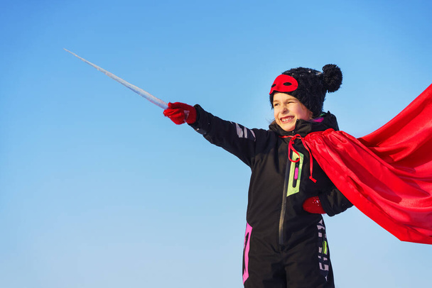 Funny little girl playing power super hero over blue sky background. Superhero concept. - Foto, Bild
