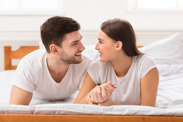 Couple Holding Hands Lying In Bed At Home - Foto, imagen