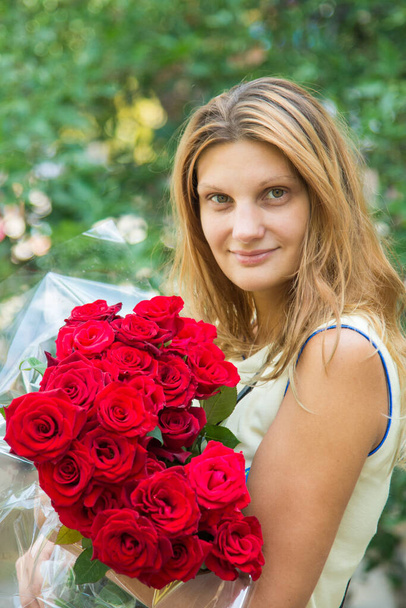 Portrait of a beautiful girl with a bouquet of roses in her hands - Foto, Bild