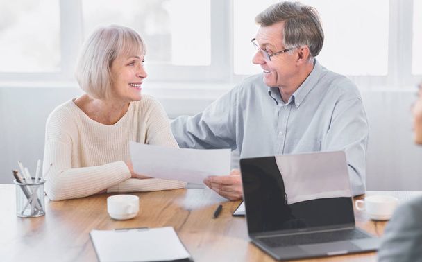 Volwassen echtpaar in gesprek met financieel adviseur op kantoor - Foto, afbeelding