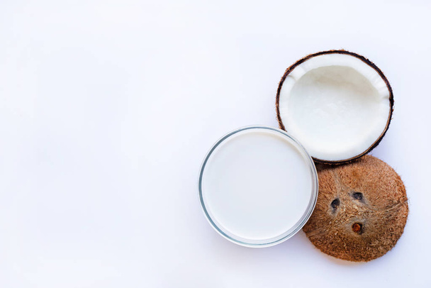 Half Coconut with glass bowl of coconut milk on white background. - Foto, Imagen