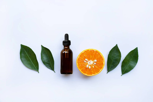 Essential oil with orange and green leaves on white background. - Foto, Imagem