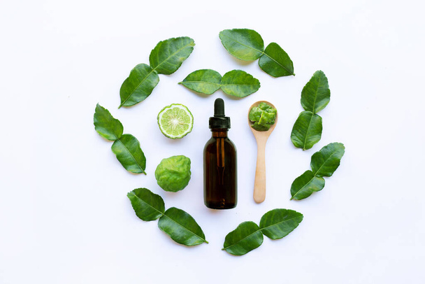 Bottle of essential oil and  fresh kaffir lime or bergamot fruit with leaves isolated on white background. - 写真・画像