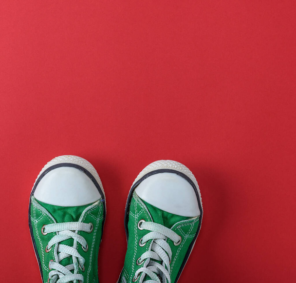 par de zapatos verdes para niños sobre un fondo rojo, vista superior, espacio para copiar
 - Foto, Imagen