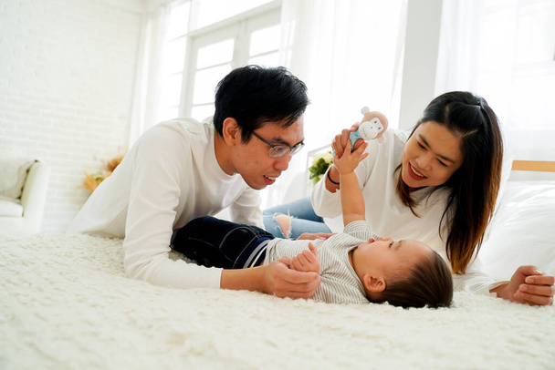 Asian family of father and mother playing toy doll with their son on bed at home - Fotografie, Obrázek