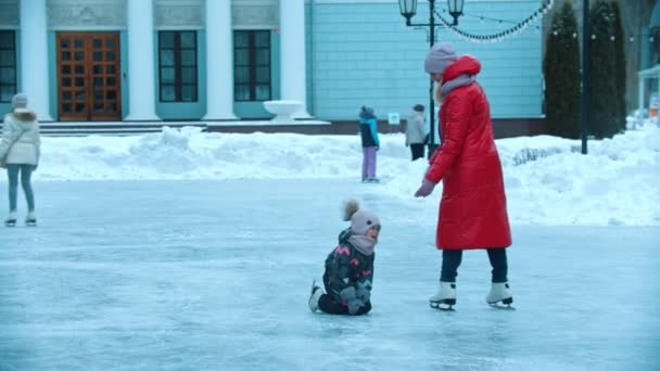 Μια νεαρή γυναίκα μητέρα πατινάρει στον πάγο με τα παιδιά της - μεγαλώνοντας το παιδί της από τον πάγο - Πλάνα, βίντεο